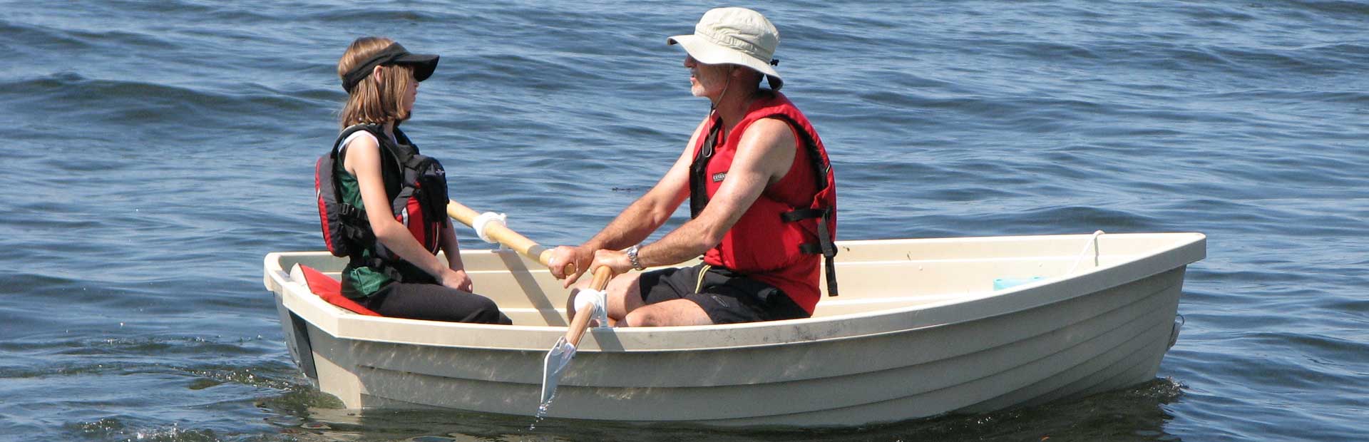 Father and daughter in small rowboat on a lake as Father rows.