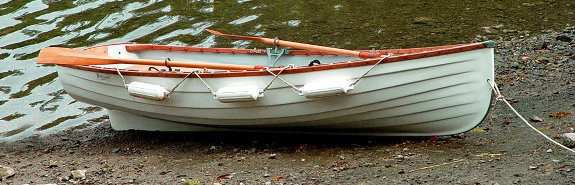 Small rowboat landed on the shore by a lake.